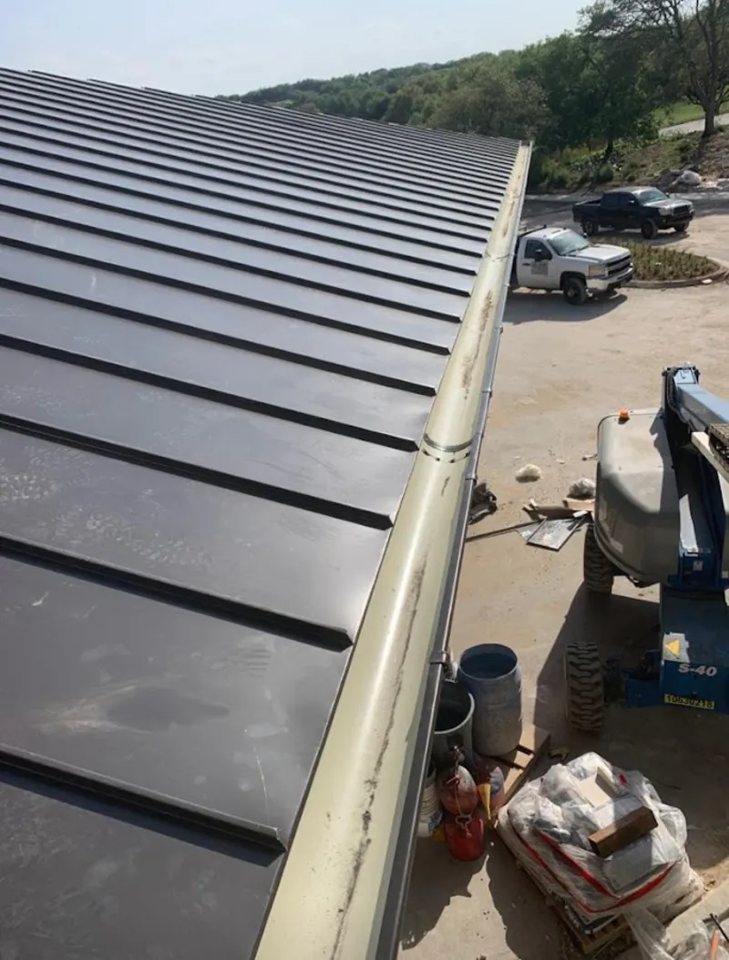 Standing seam panel and gutter detail on a metal roofing jobsite in Wharton